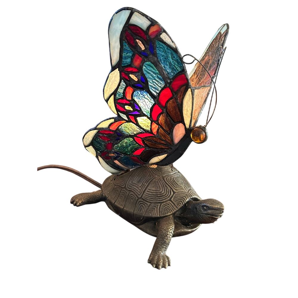 Vintage Tiffany style stained glass butterfly lamp resting on a brass turtle